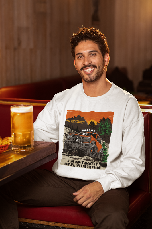 A person sitting in a booth wearing a white crewneck sweatshirt with a graphic print, displaying a cheerful expression.