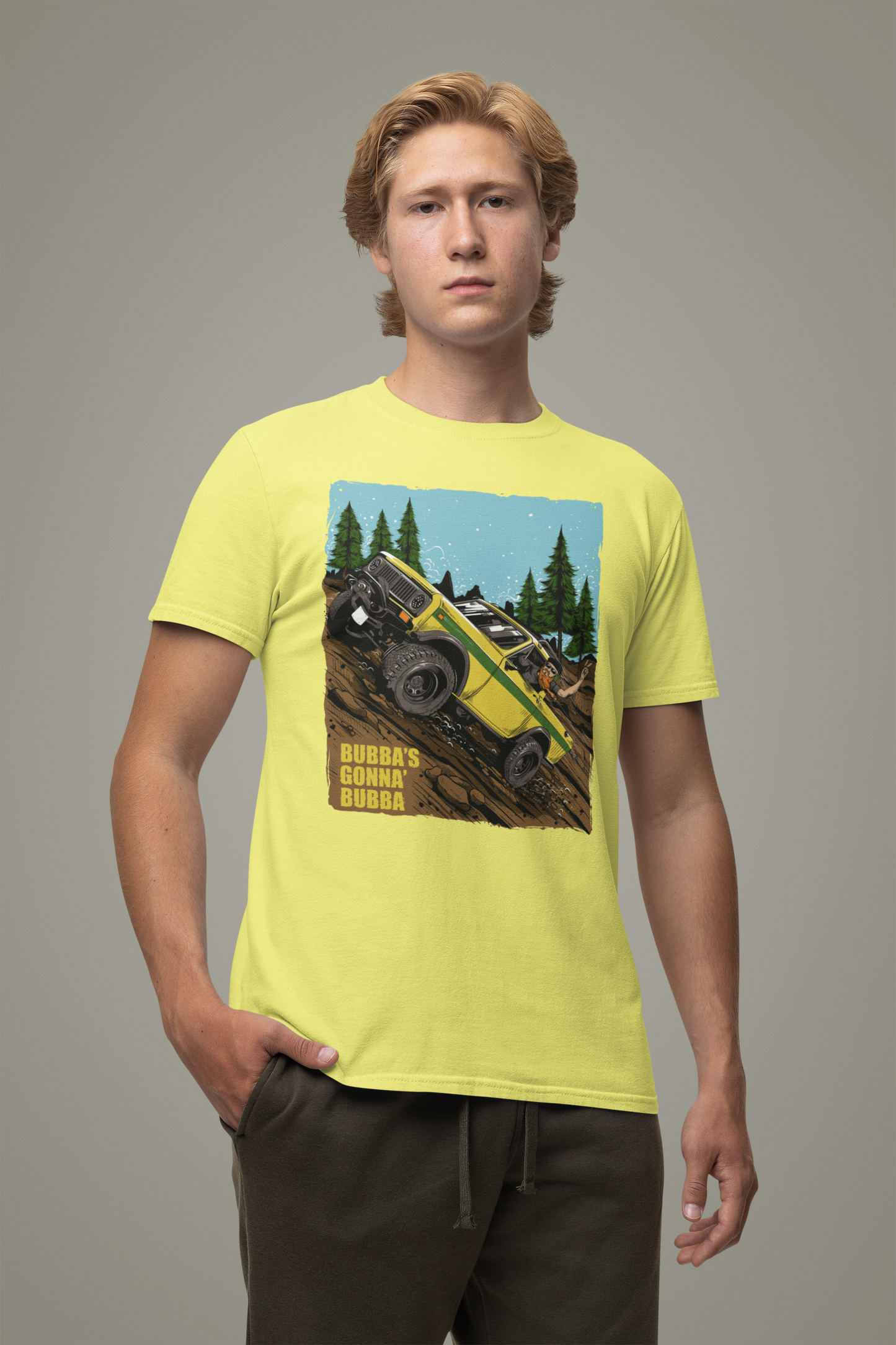 A person wearing a yellow unisex t-shirt with a graphic print of a vehicle in a natural setting.