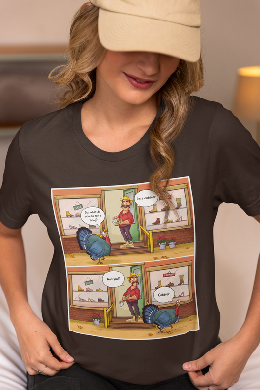 A person wearing a black unisex short-sleeve t-shirt with a colorful comic strip print in the center.