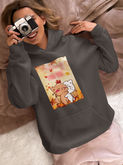A person is wearing a hoodie featuring a cartoon design of two hugging cats holding a camera.
