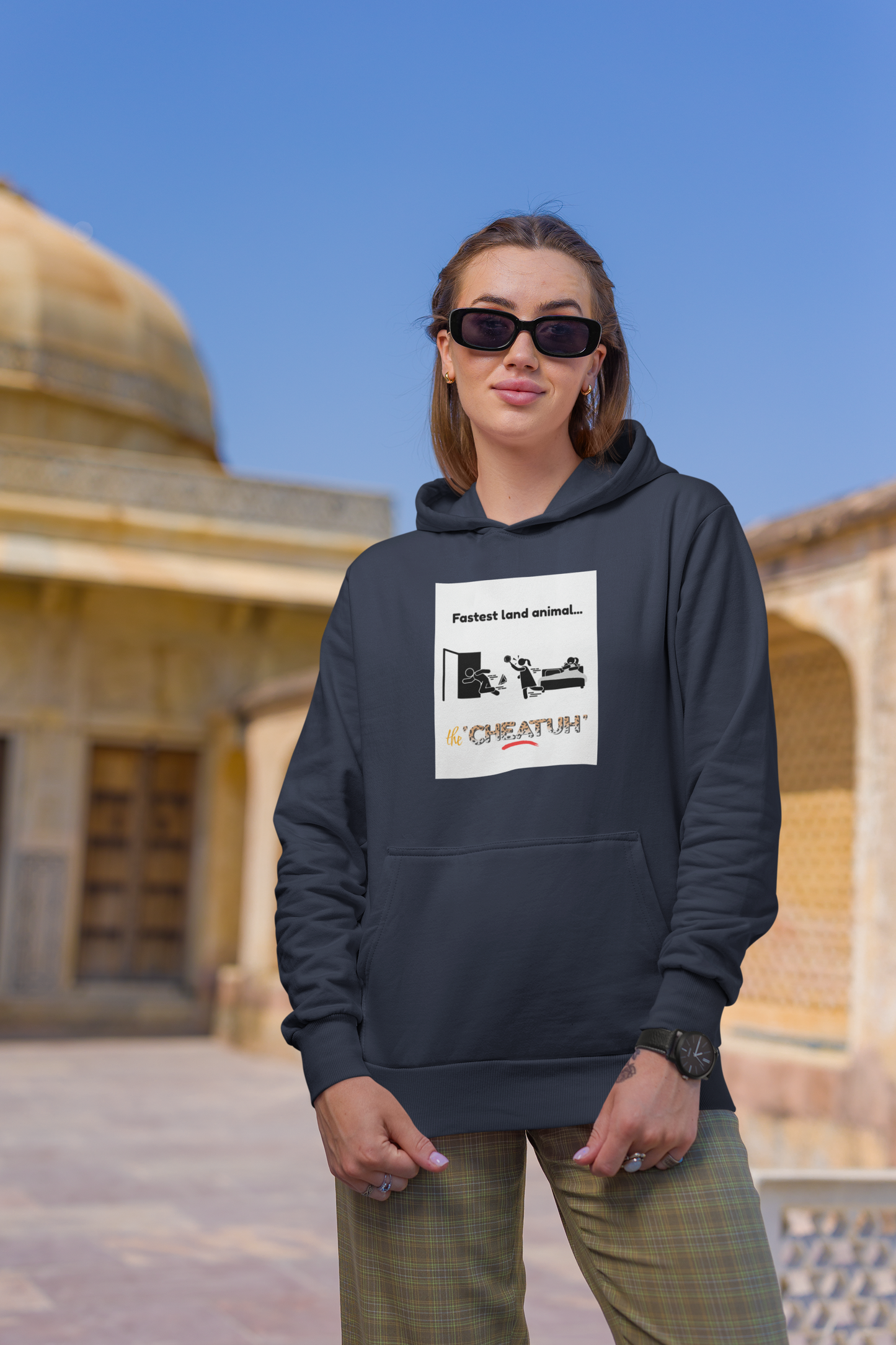 A person wearing a navy hooded sweatshirt with a graphic print, standing outdoors.