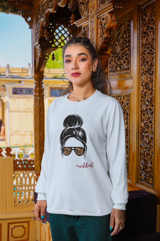 Woman wearing a white sweatshirt with a graphic design in front of an ornate wooden structure.